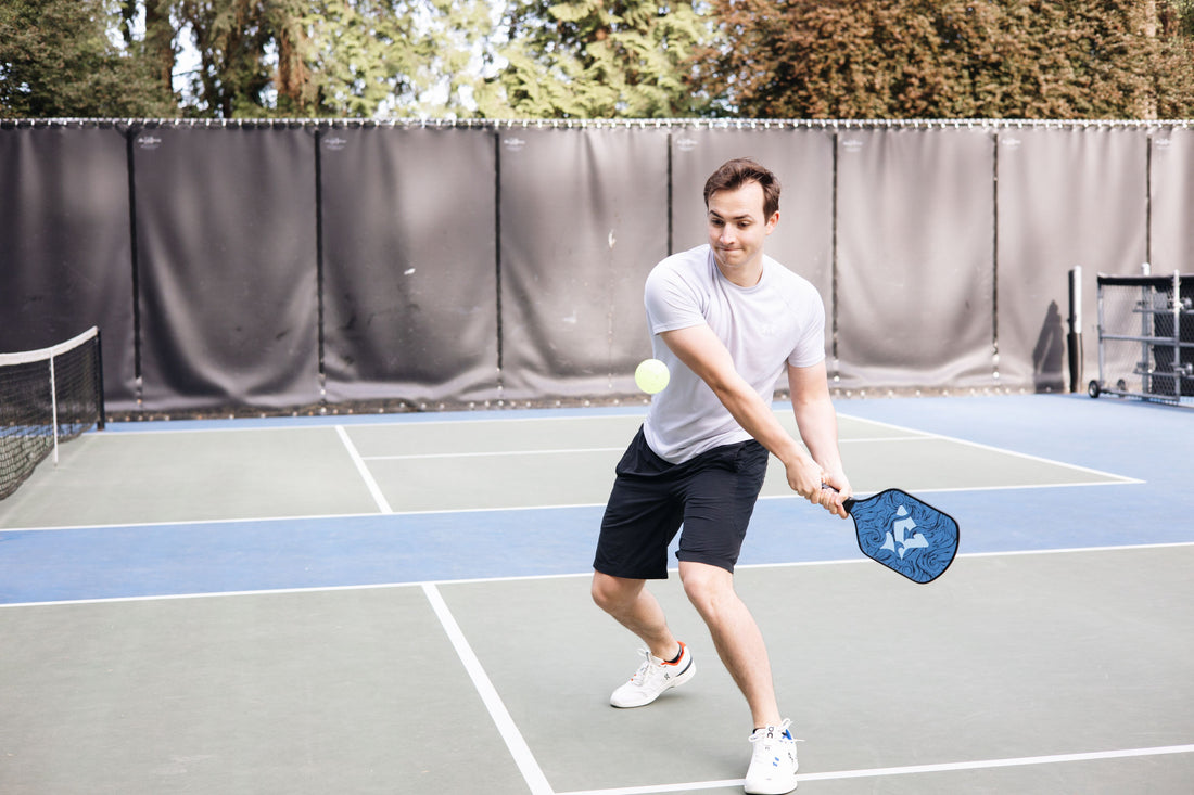Male playing a pickleball game wearing tennis shoes and using an Apiras Pickleball Paddle