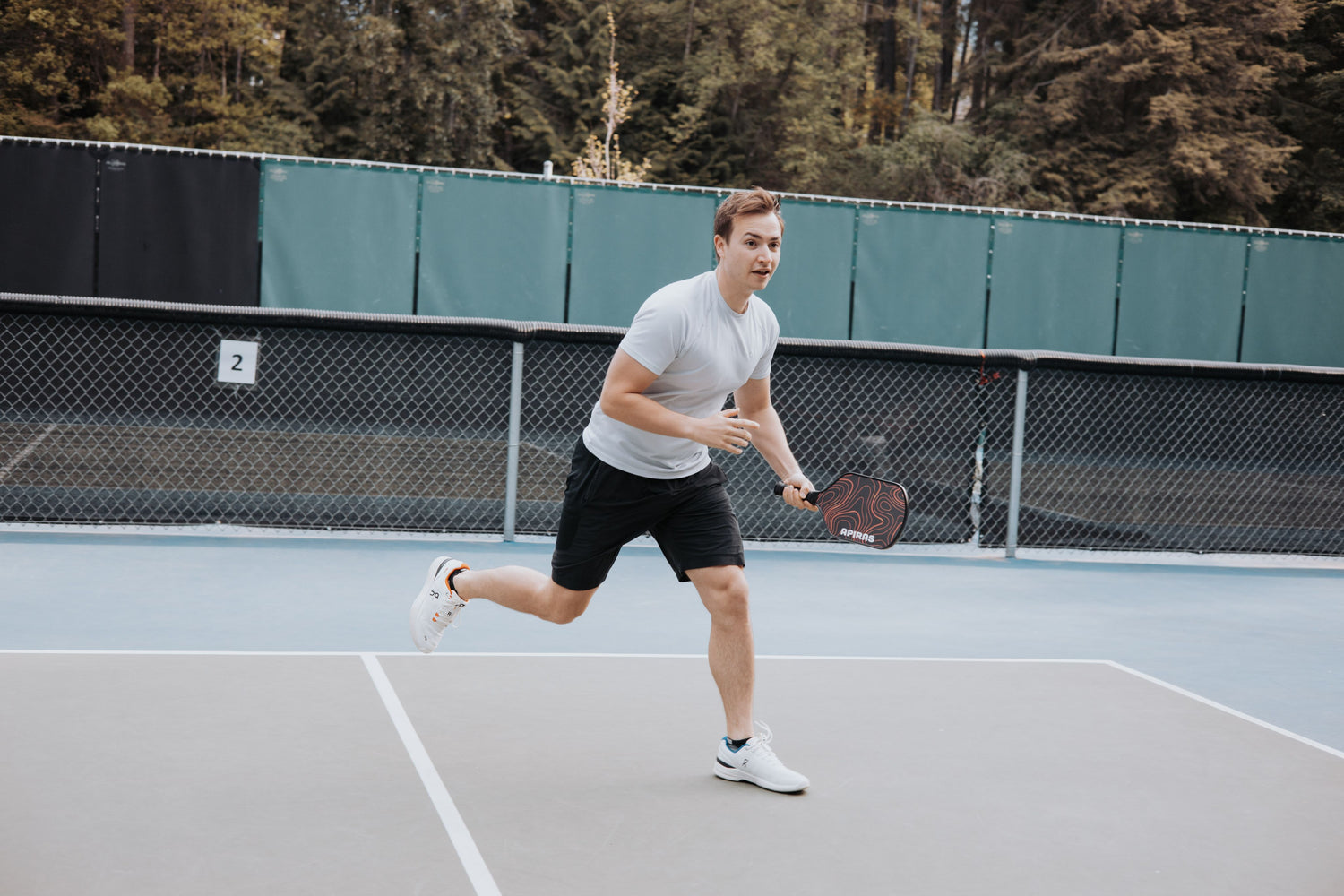 Man running towards ball on the pickleball court with a carbon fiber pickleball paddle