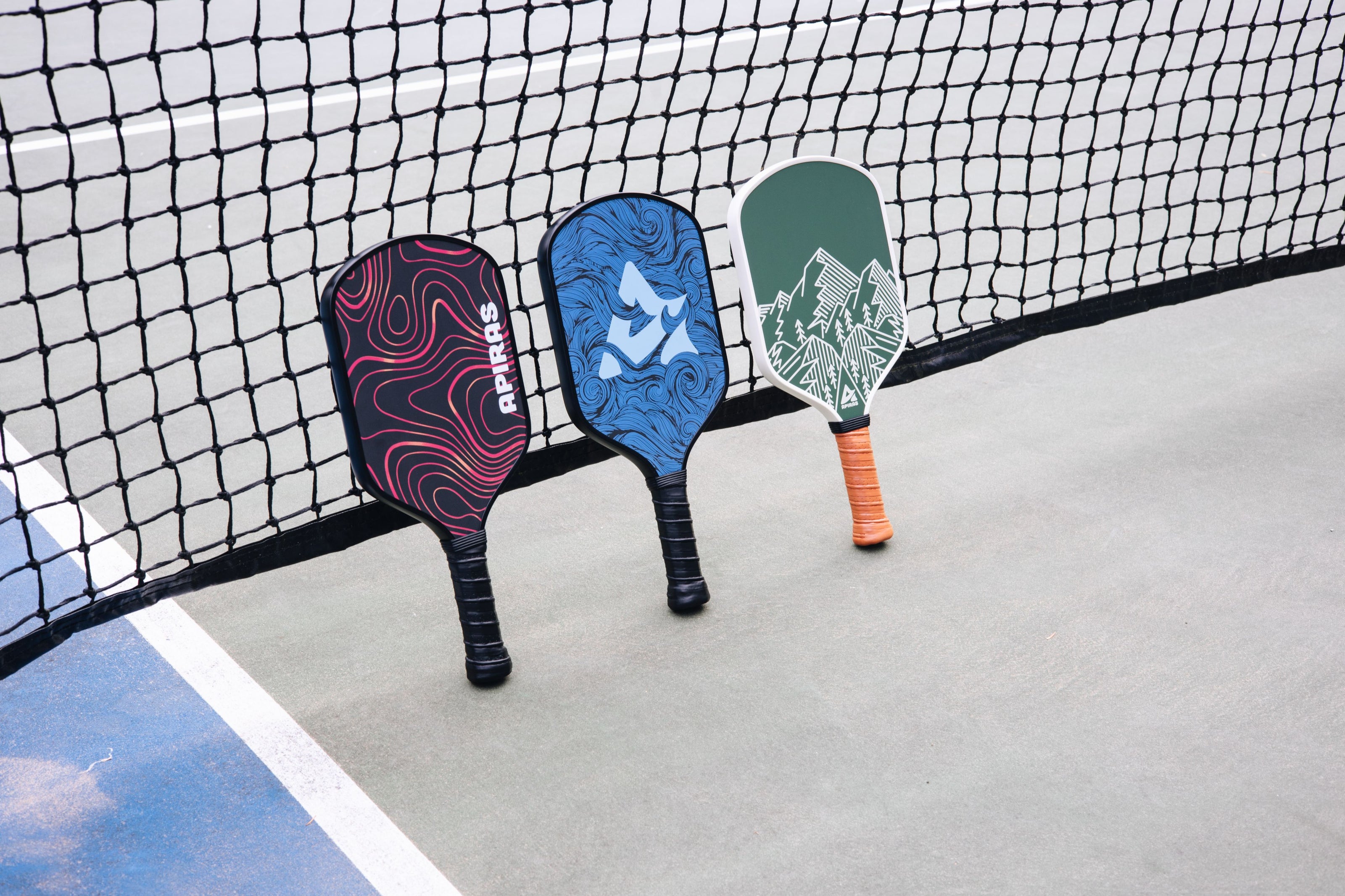 Apiras Pickleball Paddles leaning against pickleball nets